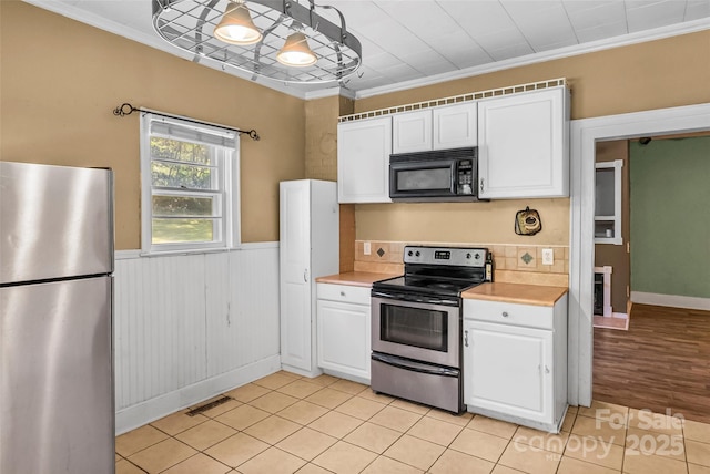 kitchen featuring white cabinets, crown molding, light countertops, stainless steel appliances, and visible vents