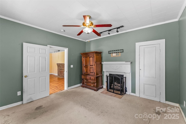 unfurnished living room featuring rail lighting, carpet, a ceiling fan, and ornamental molding