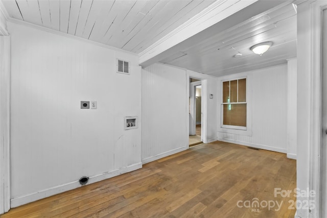 empty room with baseboards, ornamental molding, wood finished floors, and visible vents