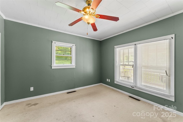 carpeted empty room featuring a ceiling fan, baseboards, visible vents, and ornamental molding