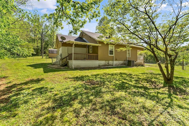 back of house with a yard, central AC unit, and roof with shingles