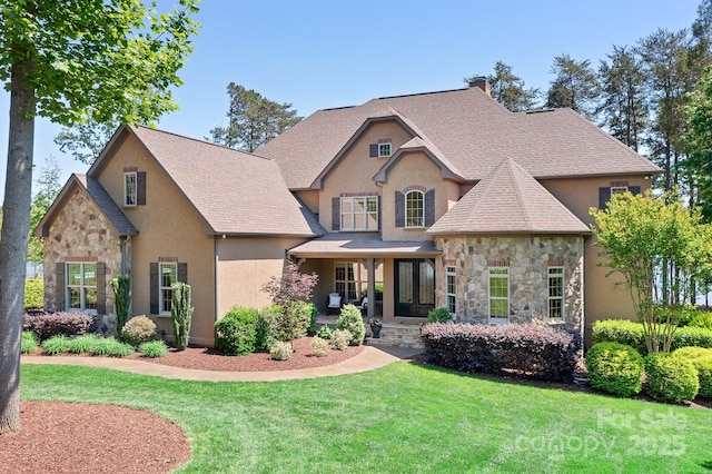 craftsman-style home with a chimney, stucco siding, a front yard, and stone siding