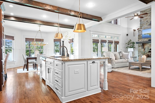 kitchen featuring a sink, light stone counters, stainless steel dishwasher, and wood finished floors