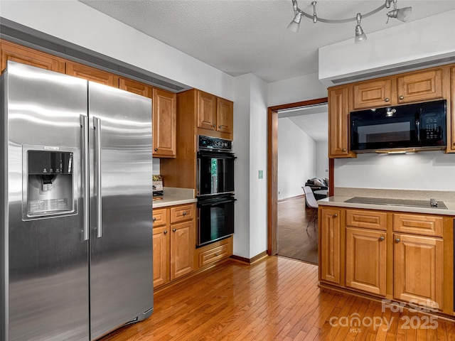 3 Governors Dr, Asheville, NC 28804 - kitchen featuring light countertops, a textured ceiling, brown cabinetry, light wood-style flooring, and black appliances