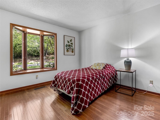 3 Governors Dr, Asheville, NC 28804 - bedroom featuring baseboards, a textured ceiling, hardwood / wood-style floors, and visible vents
