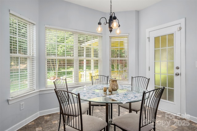 dining room with baseboards, stone finish flooring, and a notable chandelier