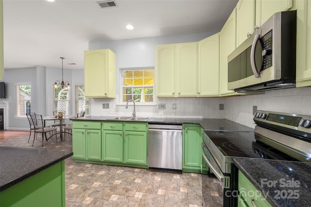kitchen featuring a sink, stainless steel appliances, tasteful backsplash, visible vents, and green cabinets
