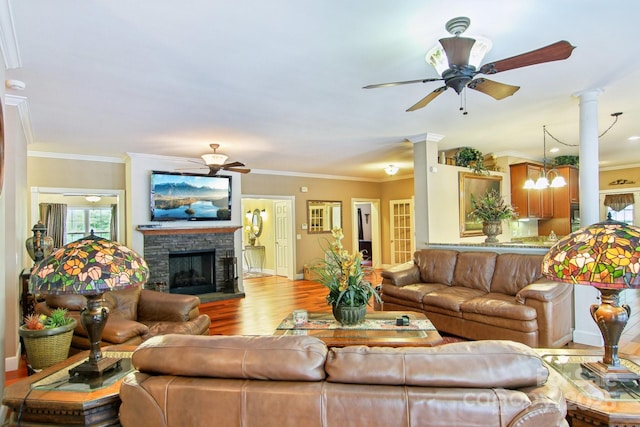 living area with a ceiling fan, baseboards, a stone fireplace, and wood finished floors