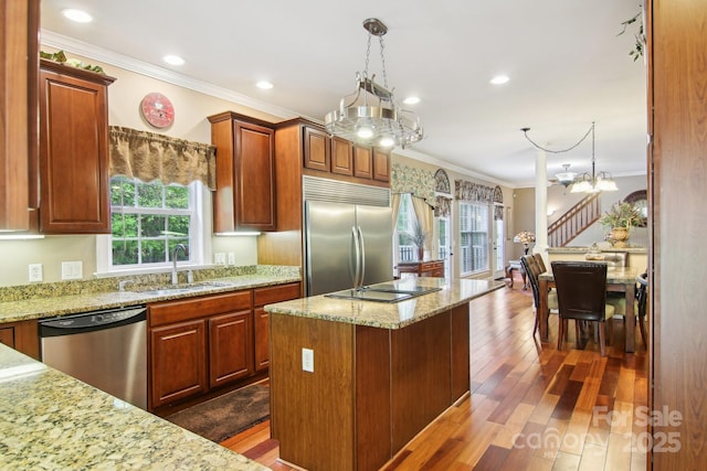 kitchen with crown molding, dark wood-style flooring, appliances with stainless steel finishes, a sink, and a chandelier