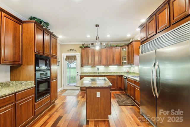 kitchen with hardwood / wood-style floors, a center island, ornamental molding, glass insert cabinets, and black appliances