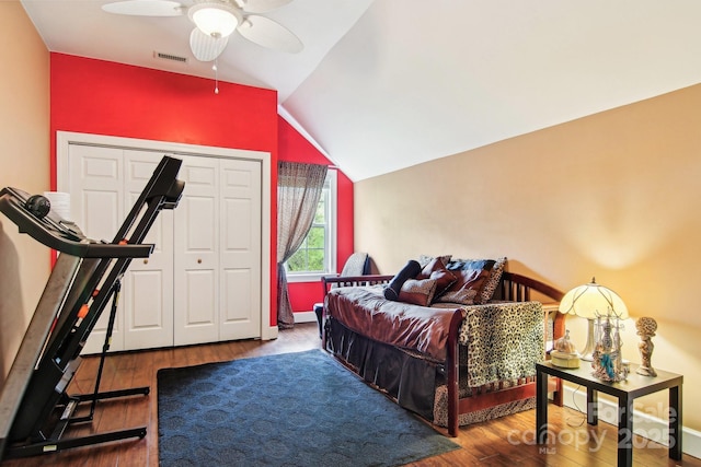 bedroom with ceiling fan, wood finished floors, vaulted ceiling, visible vents, and a closet