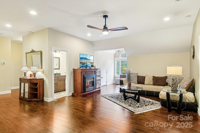 living room featuring a glass covered fireplace, ceiling fan, wood finished floors, and lofted ceiling