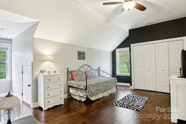 bedroom with a closet, baseboards, ceiling fan, dark wood-type flooring, and vaulted ceiling