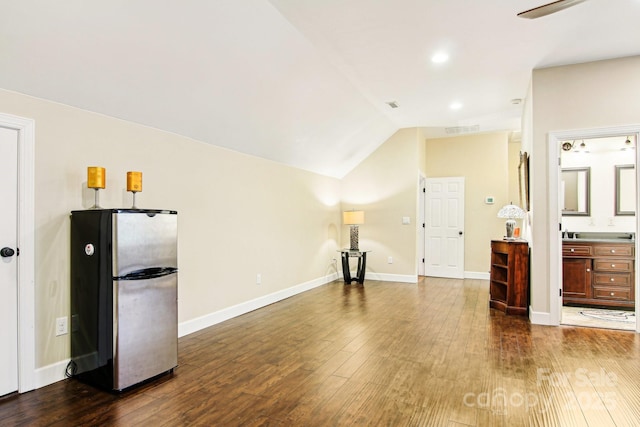 unfurnished living room featuring visible vents, baseboards, lofted ceiling, and dark wood-style floors