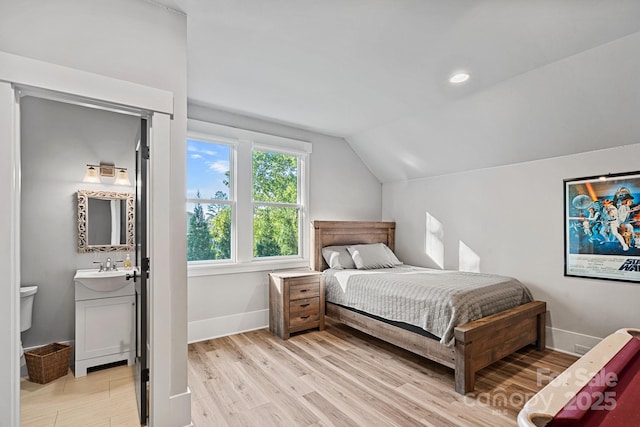 bedroom featuring a sink, light wood-type flooring, vaulted ceiling, baseboards, and recessed lighting
