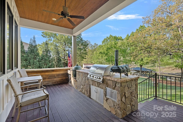 wooden deck with grilling area, a ceiling fan, a lawn, and area for grilling