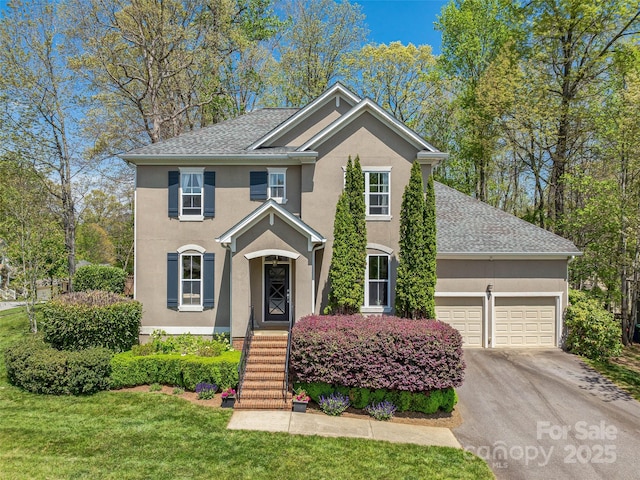 view of front of home featuring a front lawn, stucco siding, an attached garage, driveway, and roof with shingles