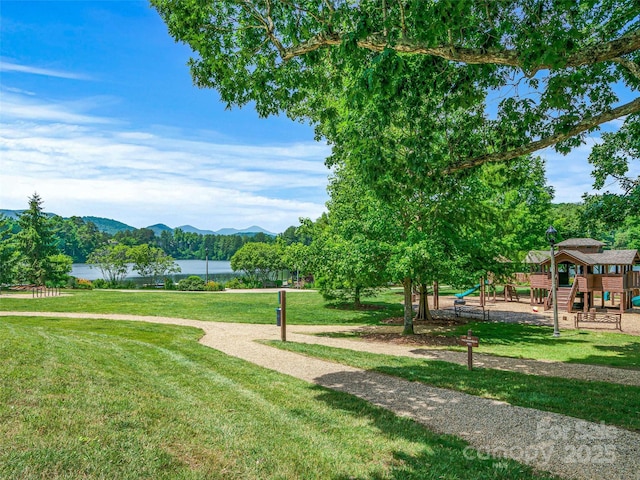 view of community with a yard, playground community, and a water and mountain view