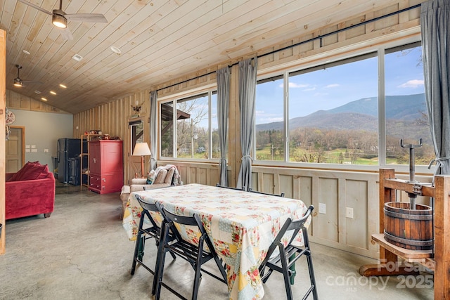 dining space featuring a mountain view, lofted ceiling, a ceiling fan, concrete floors, and wooden ceiling