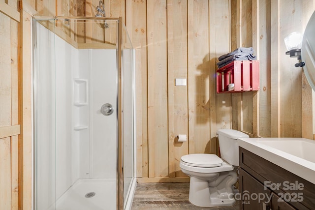 full bath with toilet, wood finished floors, vanity, and a stall shower