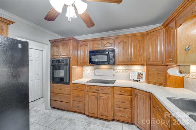 kitchen featuring black appliances, crown molding, light stone countertops, light tile patterned flooring, and backsplash