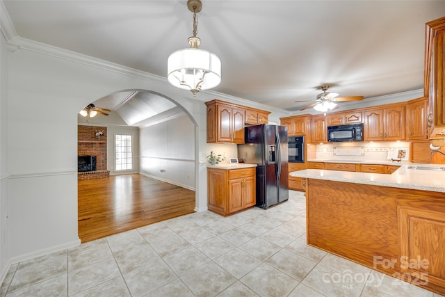 kitchen featuring black appliances, ceiling fan, a sink, a fireplace, and light countertops