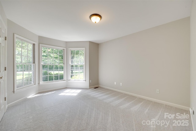 carpeted spare room featuring baseboards