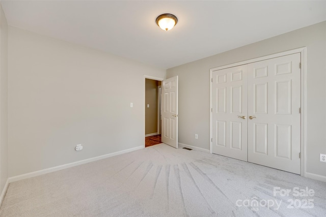 unfurnished bedroom featuring light colored carpet, baseboards, and a closet