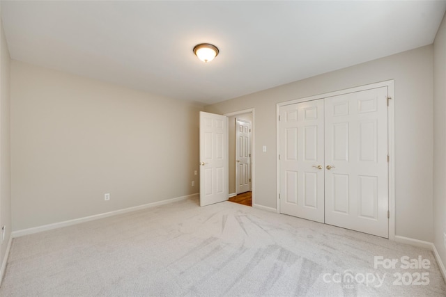 unfurnished bedroom with baseboards, carpet flooring, and a closet
