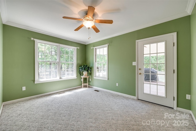 spare room with crown molding, ceiling fan, carpet floors, and baseboards