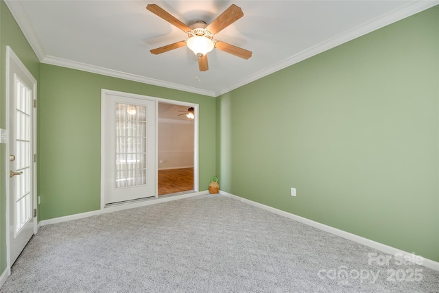 empty room with ornamental molding, carpet floors, baseboards, and ceiling fan