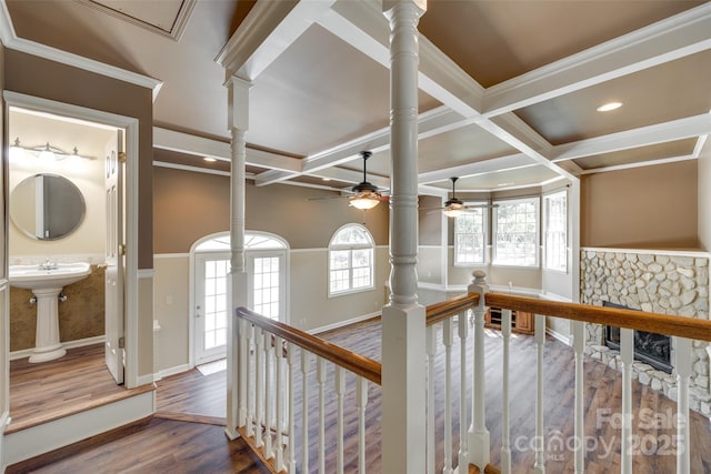 hall featuring wood finished floors, ornate columns, coffered ceiling, an upstairs landing, and beam ceiling