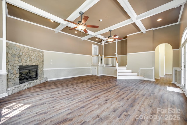 unfurnished living room featuring a ceiling fan, coffered ceiling, beamed ceiling, wood finished floors, and a fireplace