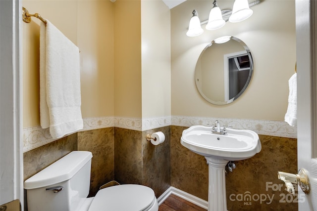 bathroom with tile walls, toilet, and wainscoting