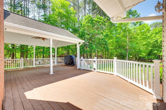 wooden deck with ceiling fan and view of wooded area