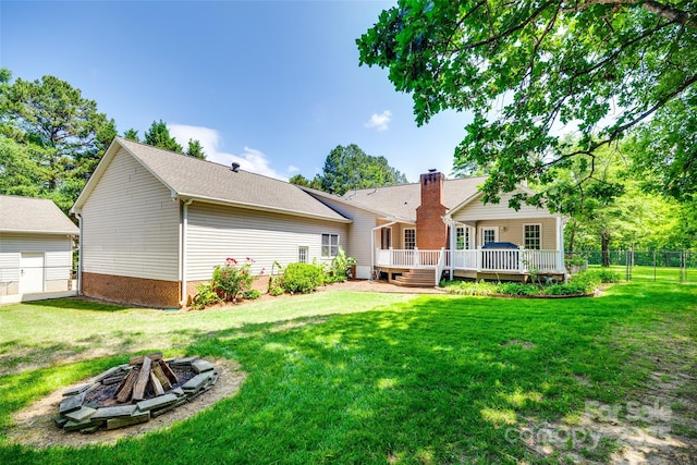 back of property with a fire pit, a deck, and a chimney