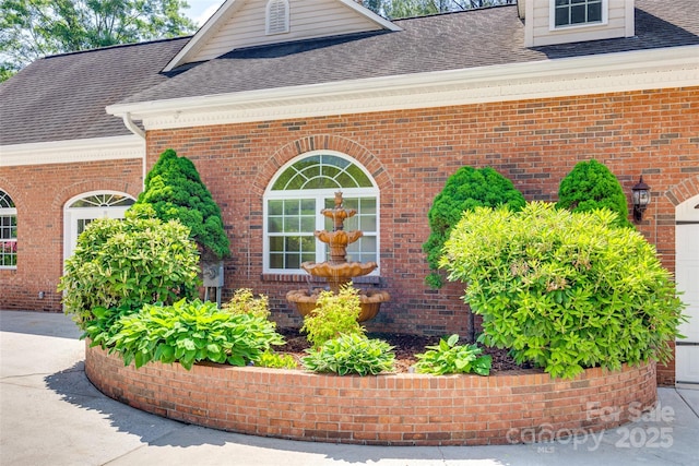 view of side of home featuring a shingled roof and brick siding