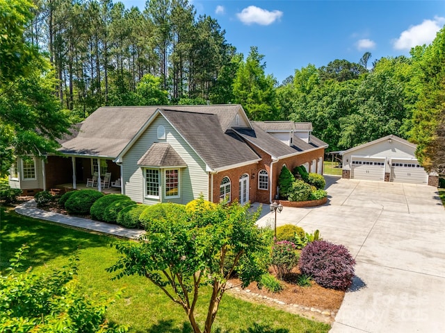 view of front of home featuring a detached garage, brick siding, a front yard, an outbuilding, and a porch