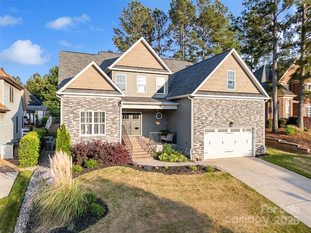 craftsman house with stone siding, an attached garage, a front lawn, and concrete driveway