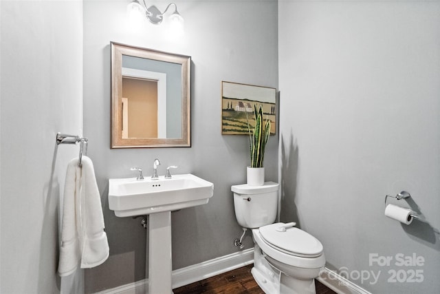 bathroom featuring wood finished floors, baseboards, a sink, and toilet