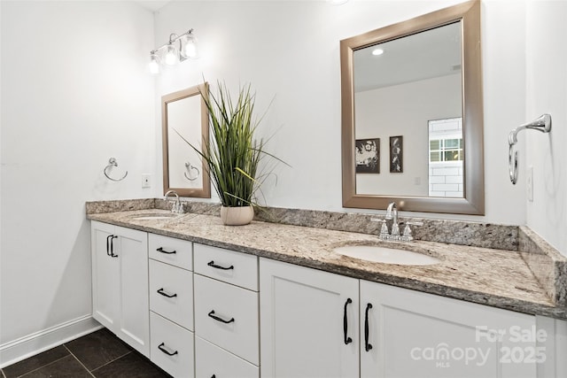 bathroom with double vanity, tile patterned flooring, baseboards, and a sink