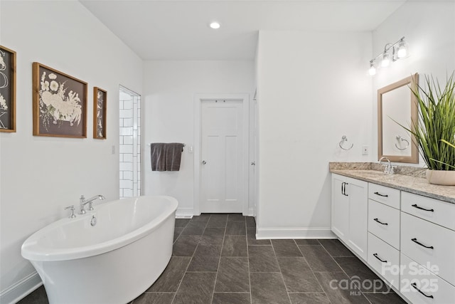 full bathroom featuring a freestanding bath, baseboards, and vanity