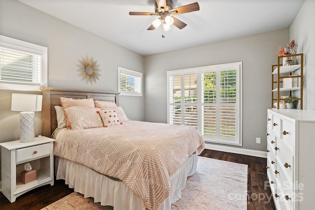 bedroom featuring dark wood finished floors, ceiling fan, baseboards, and multiple windows