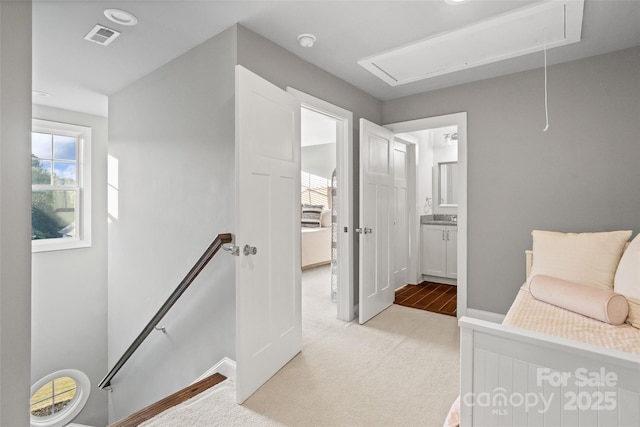 bedroom featuring attic access, light carpet, visible vents, baseboards, and connected bathroom