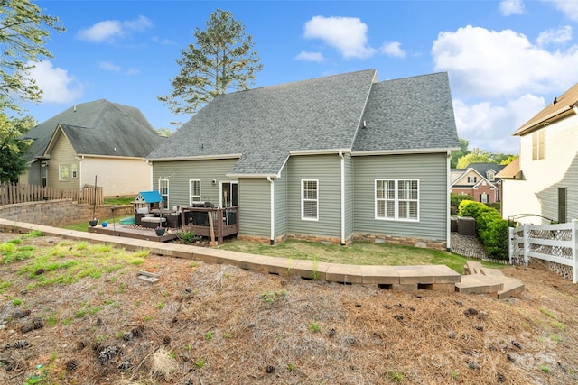 back of property with a wooden deck, central AC unit, a shingled roof, and fence private yard