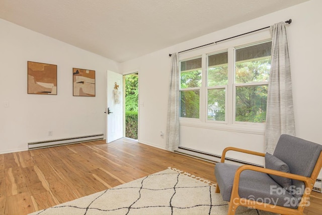 sitting room featuring wood finished floors, a baseboard heating unit, and baseboard heating