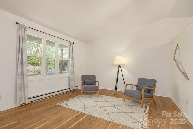 sitting room featuring baseboard heating, baseboards, wood finished floors, and vaulted ceiling