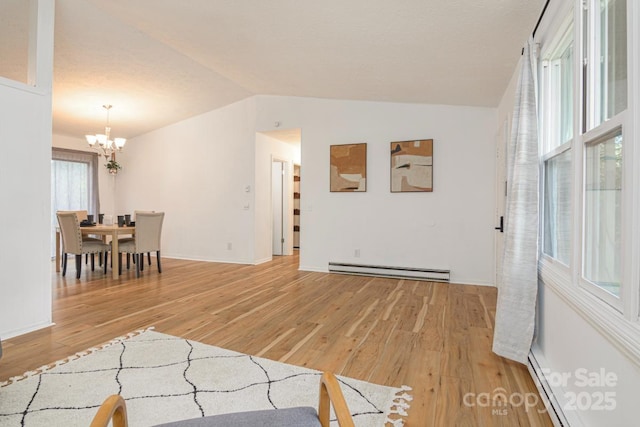 living area with baseboard heating, a notable chandelier, light wood finished floors, and vaulted ceiling