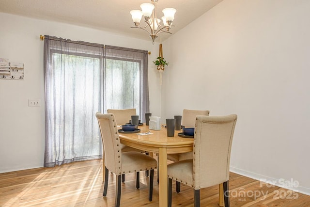 dining area featuring baseboards, a notable chandelier, and light wood finished floors