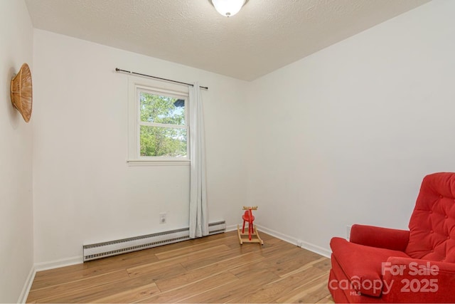 living area with light wood-style flooring, baseboard heating, and baseboards